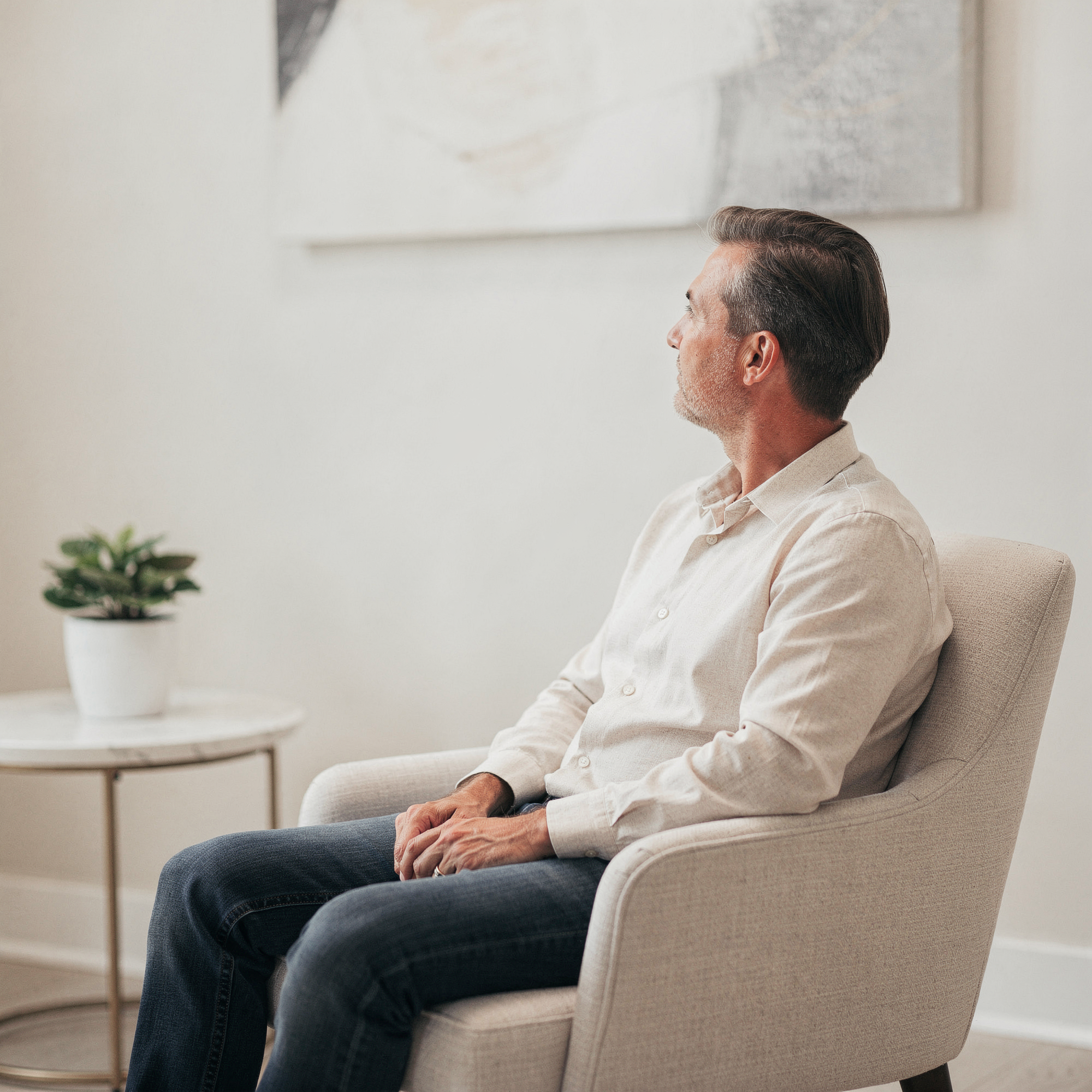 Man sitting in a waiting room chair in a light-filled medical office